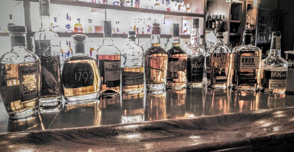 a photo of the 11 best bourbons under $50 lined up on a bar